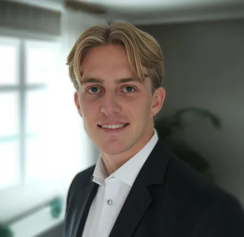 Nikolai Dokken smiling in a white shirt and suit jacket